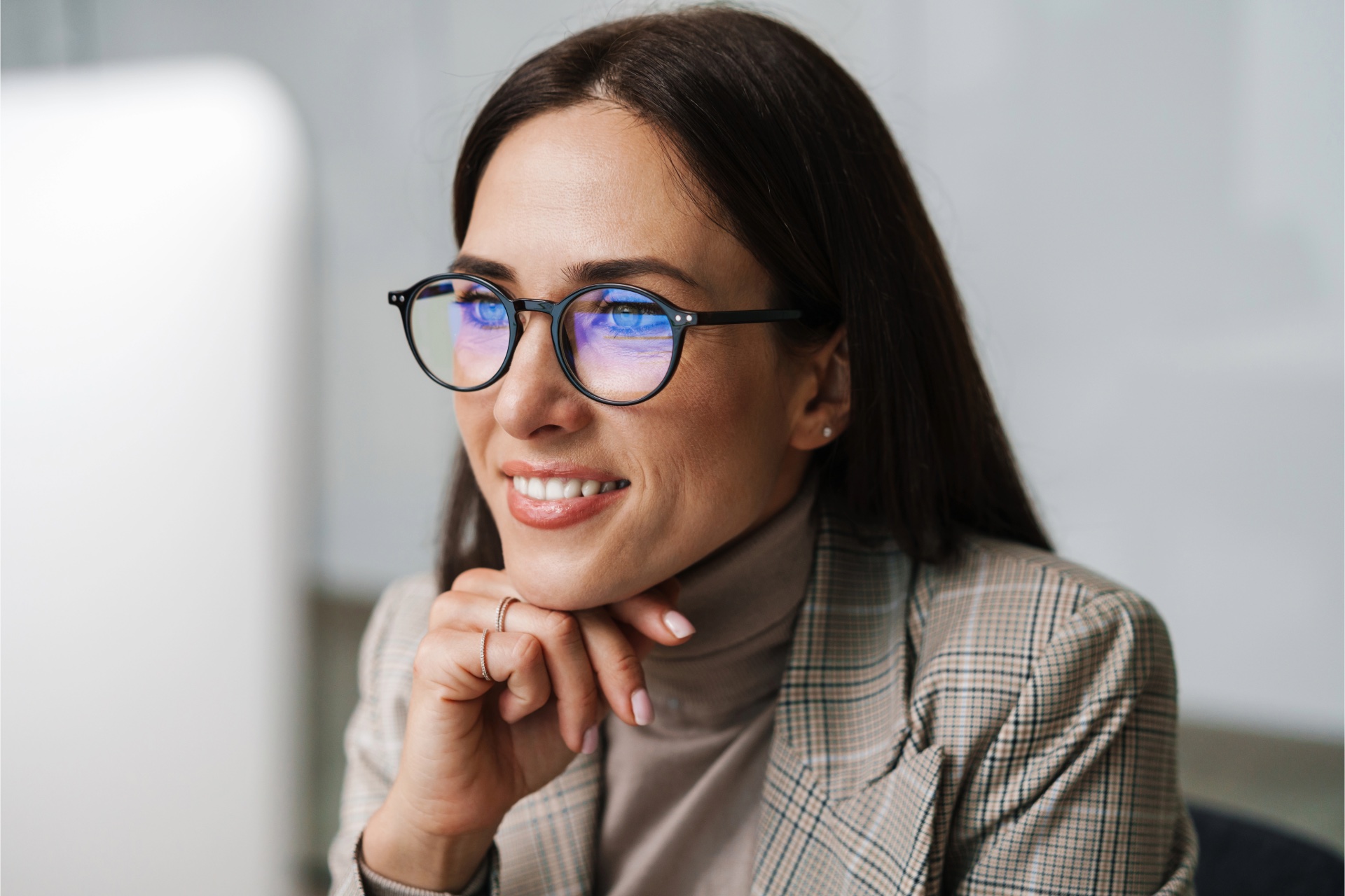 Smiling woman wearing eyeglasses while looking at a computer screen