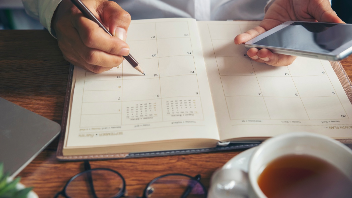 Hands using a phone over an open appointment calendar