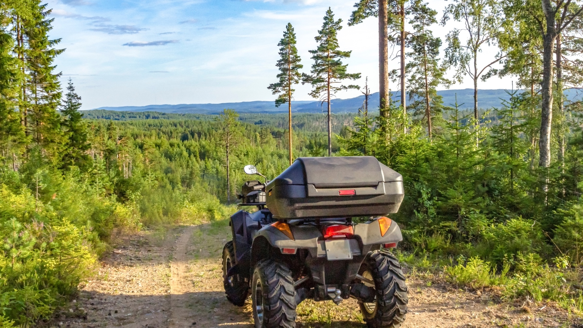 ATV parked on a trail overlooking a green forest