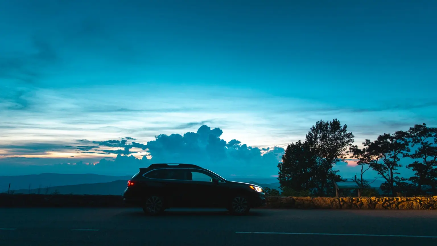 Car parked beside an open road at sunset