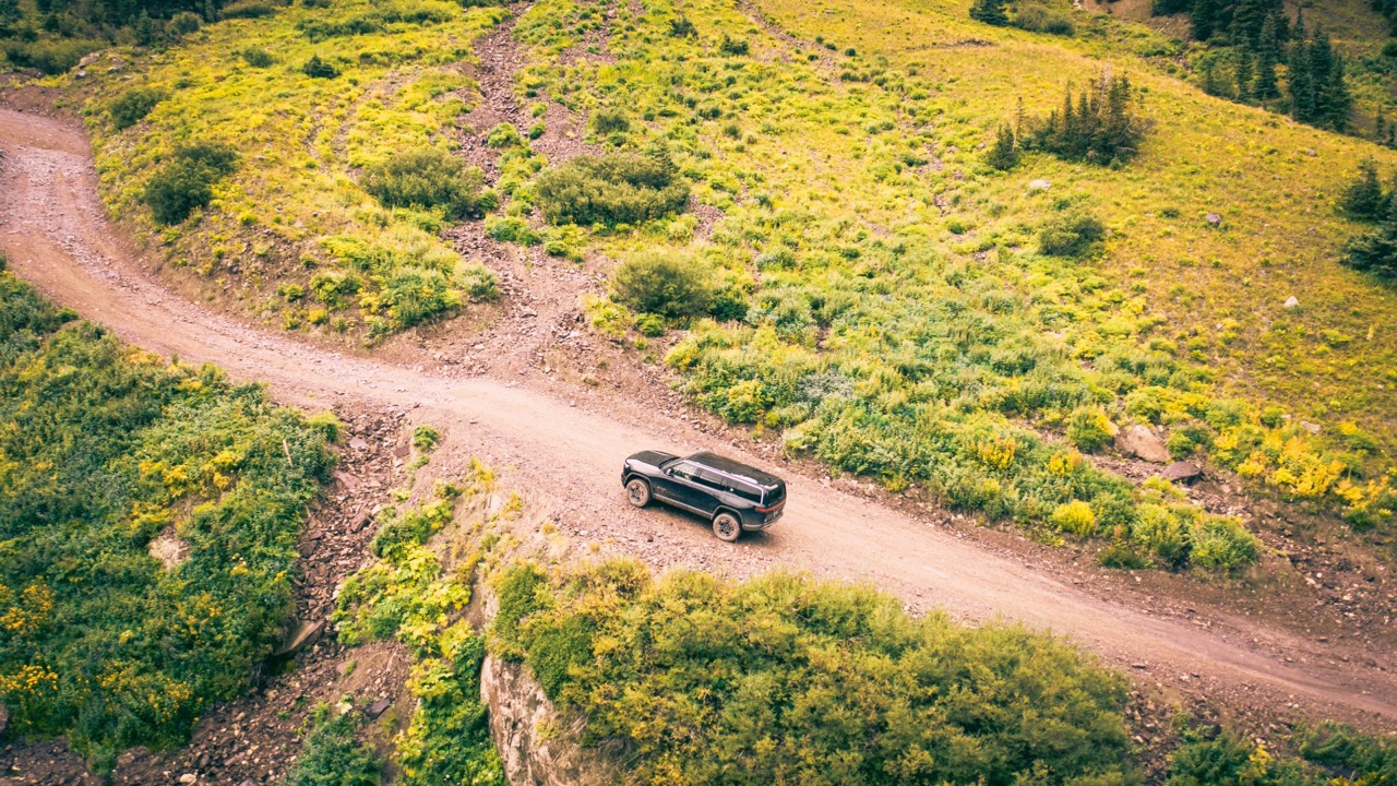 Dark Rivian SUV driving along a mountain road