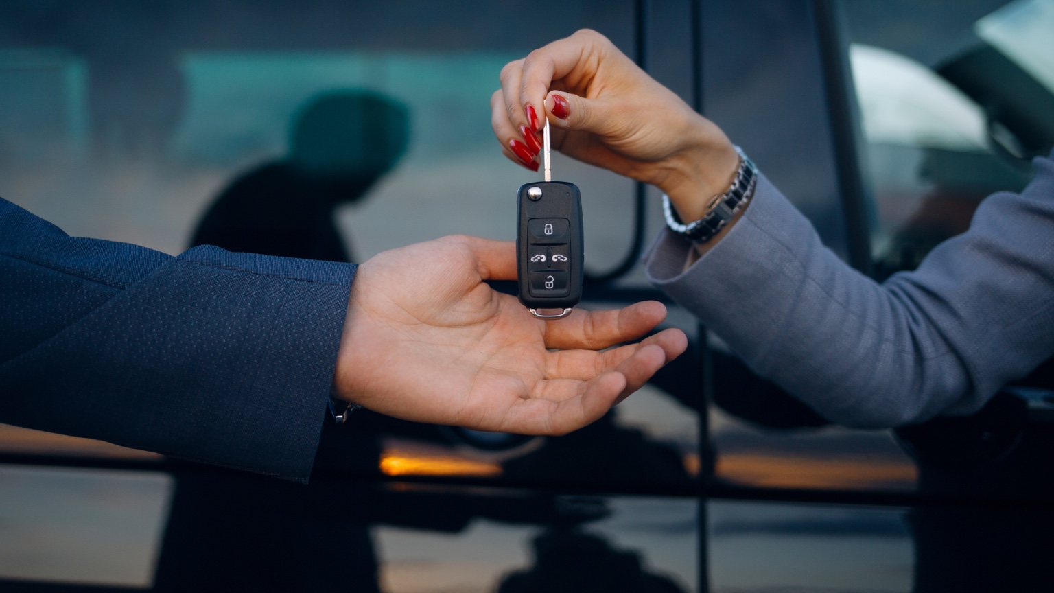 Rental car representative handing a vehicle key to a customer