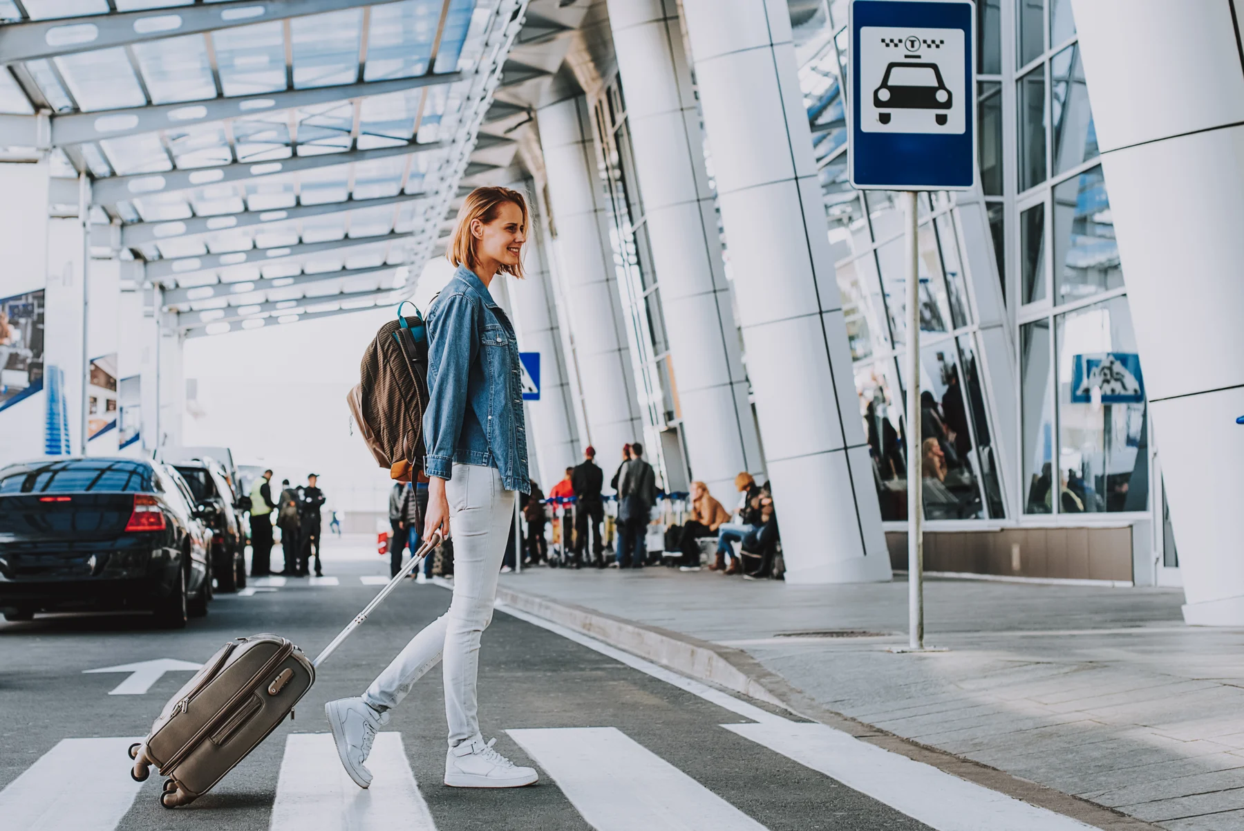Traveler walking with a suitcase outside an airport terminal