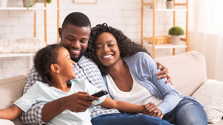 Parents relaxing with their child on a sofa at home