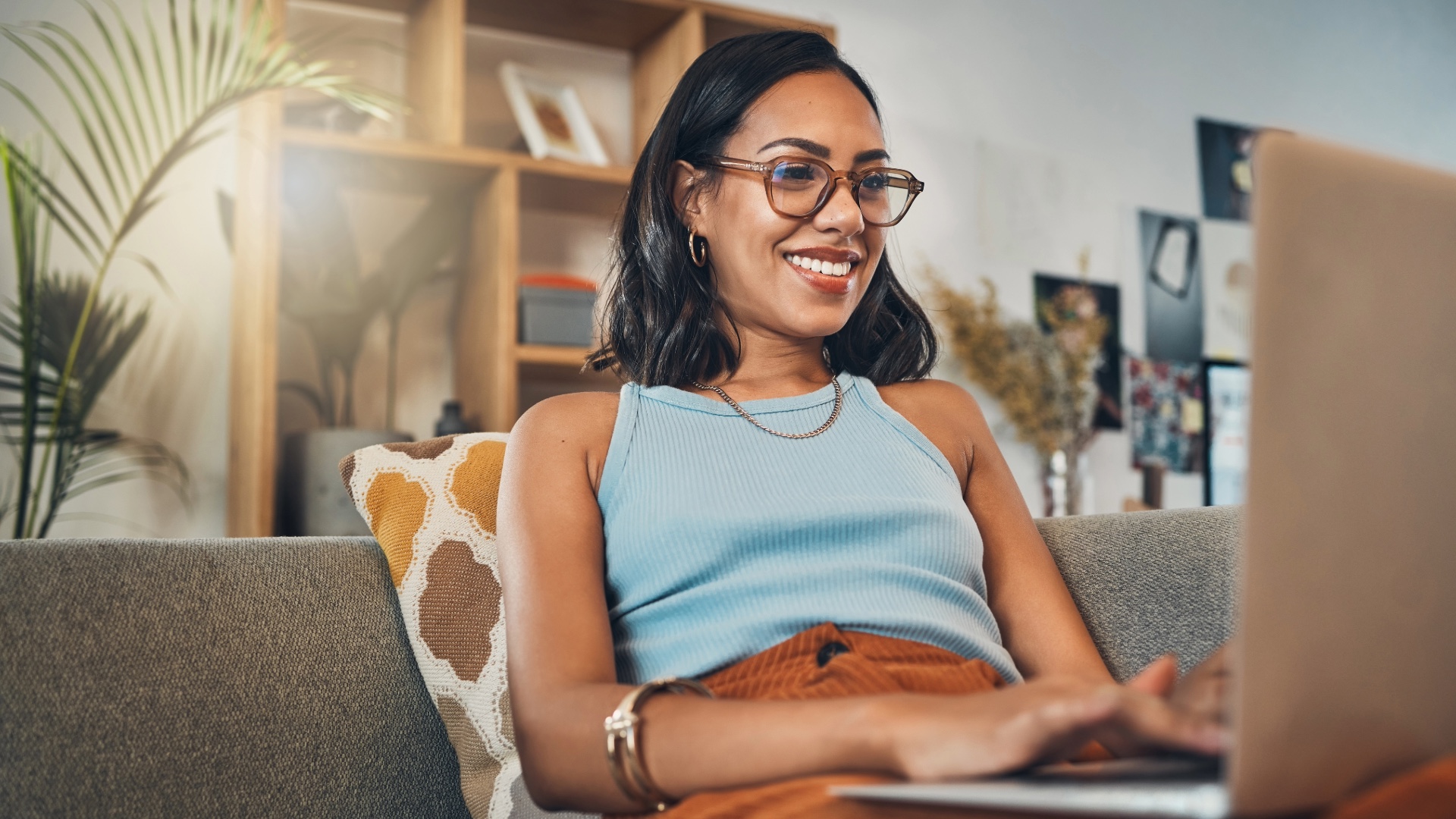 Woman wearing eyeglasses looks at a laptop while seated at home