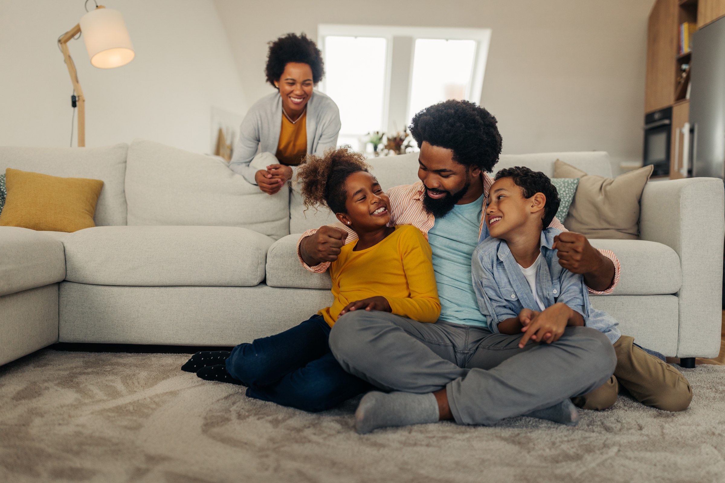 Parents smiling with their two children in a living room.