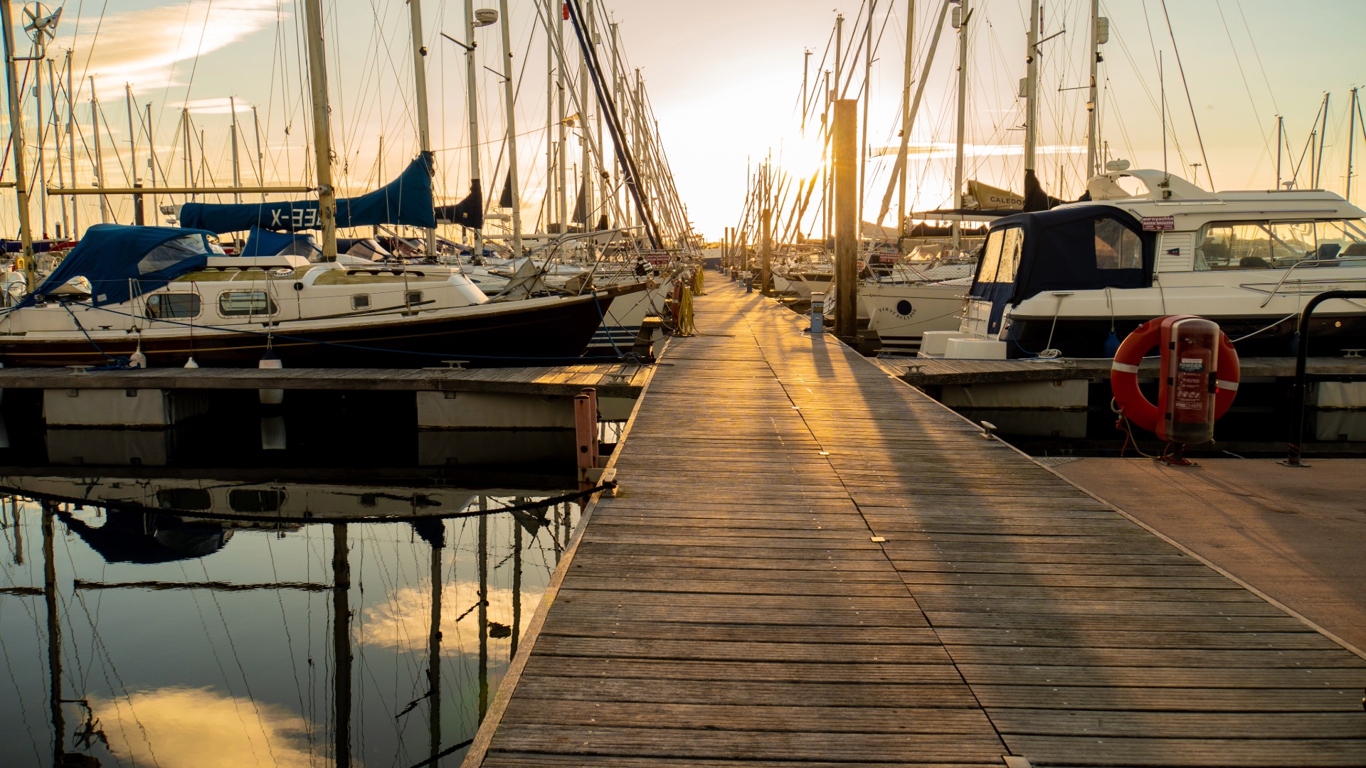 Boats moored along a marina dock at sunset