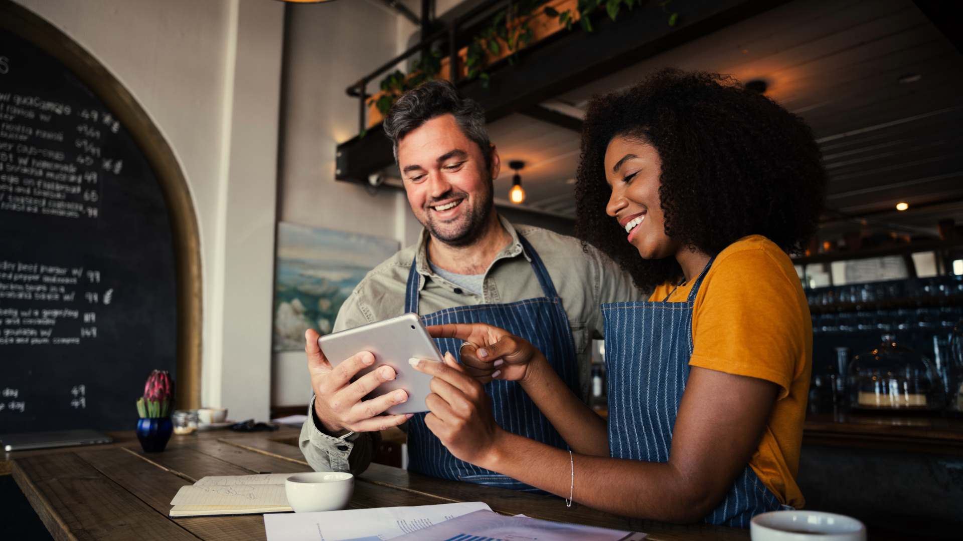 Two small-business owners reviewing a tablet together in their cafe