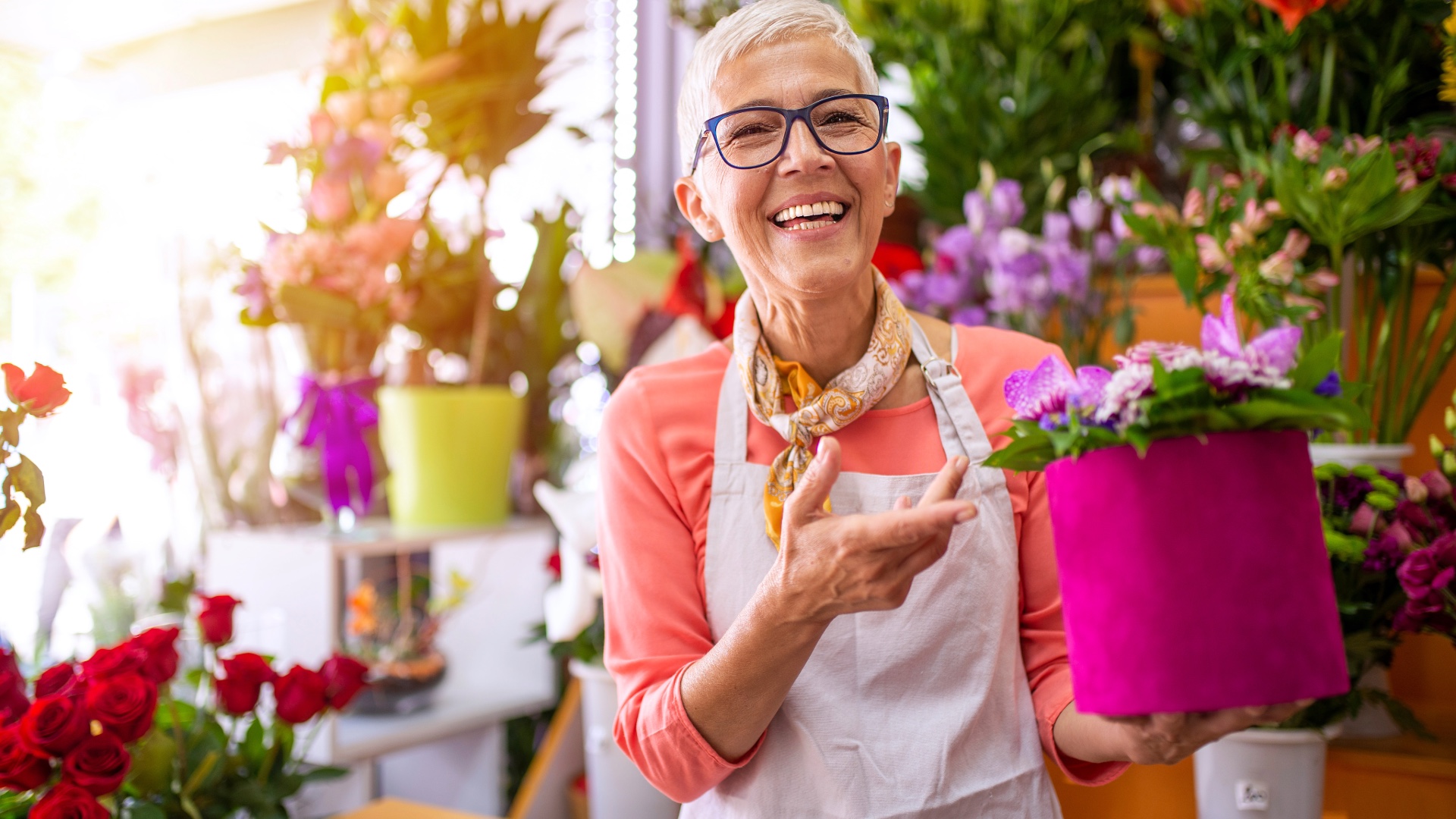 Florist holding a colorful arrangement in her shop