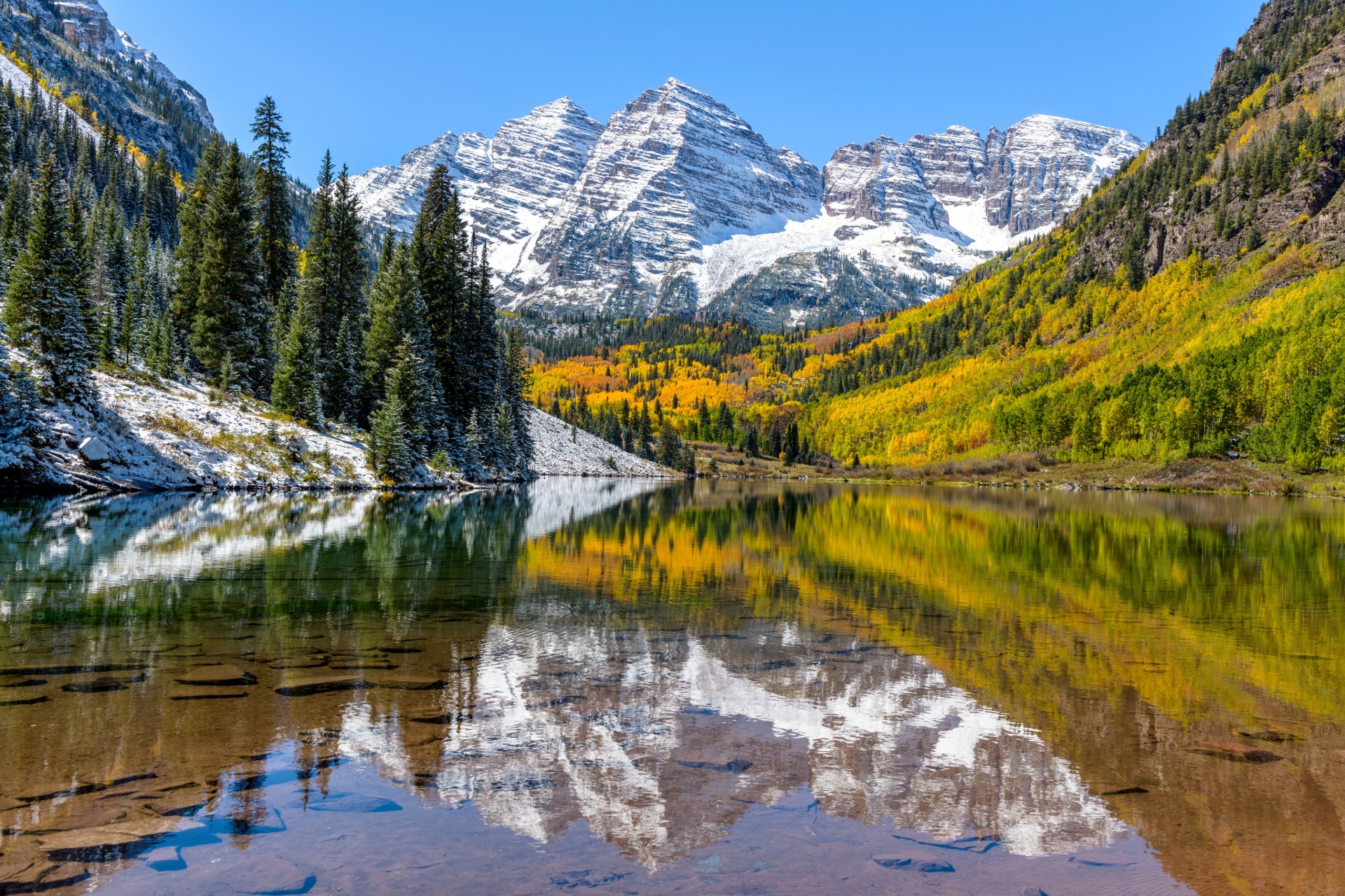 Snow-dusted Maroon Bells and autumn foliage reflected in Maroon Lake near Aspen, Colorado