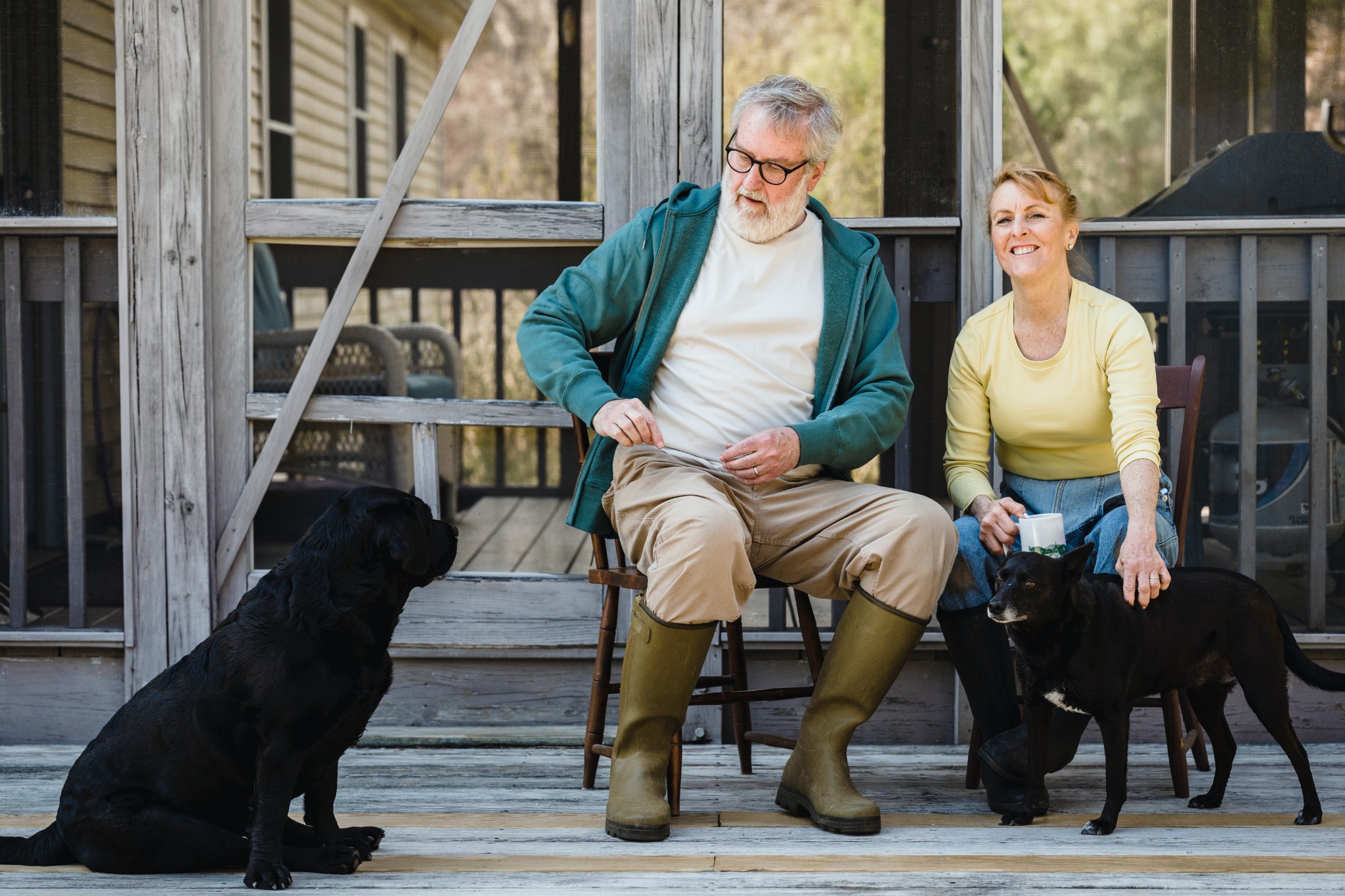 Older couple sitting together with their dogs outside their home