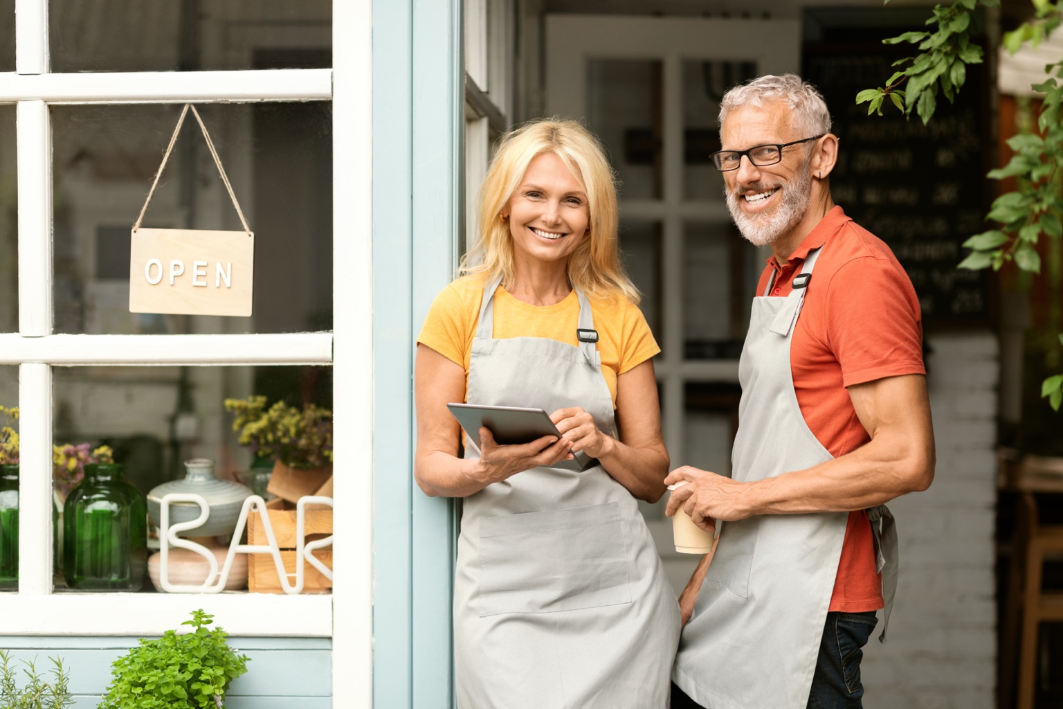 Two small-business owners standing at the entrance to their shop