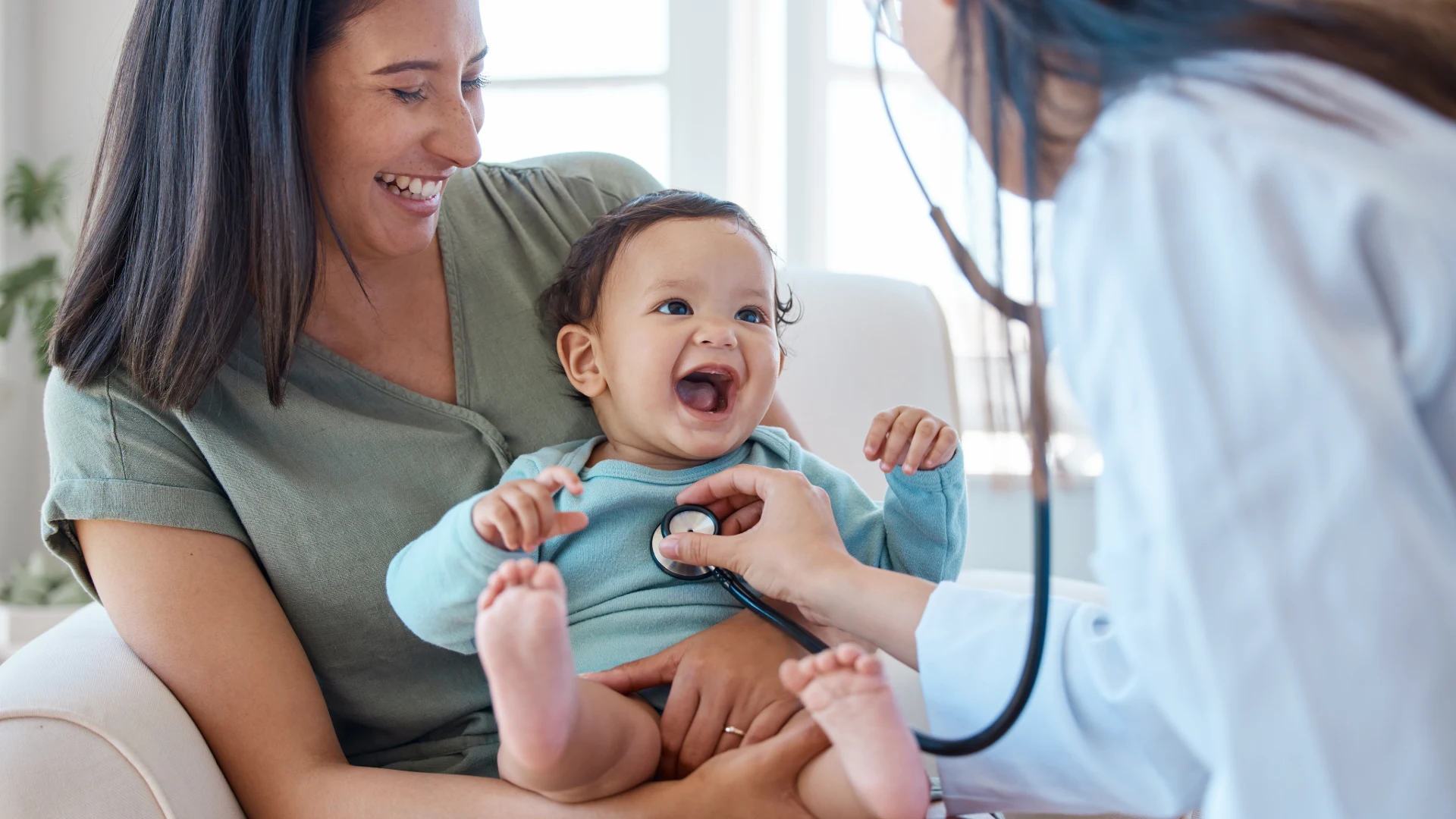 Mother holding her baby during a checkup with a doctor