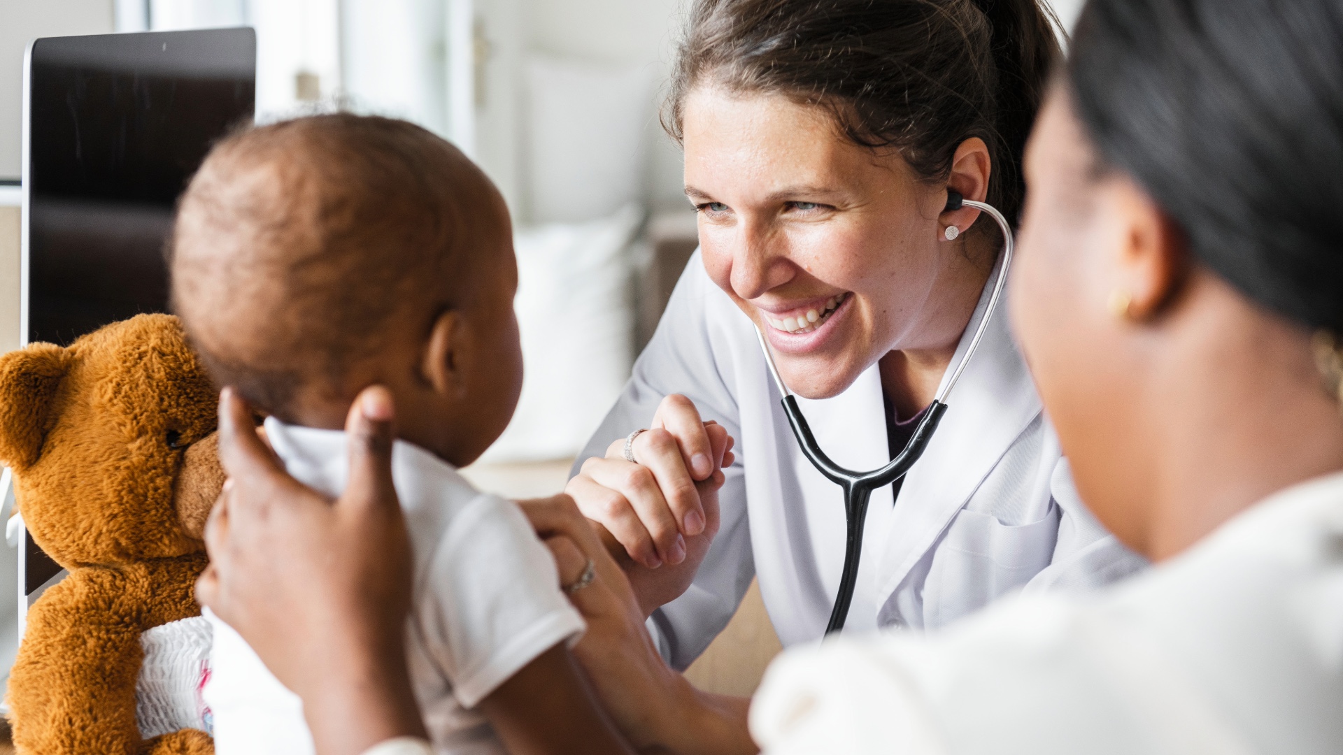 Pediatrician caring for a baby with a parent nearby