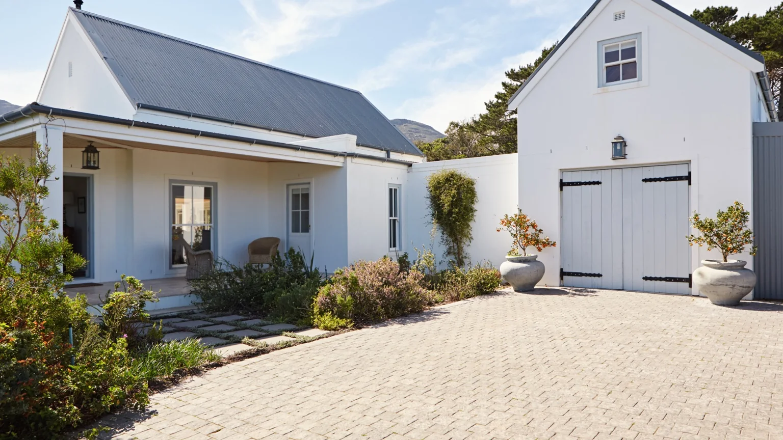 White home and detached garage with a landscaped courtyard
