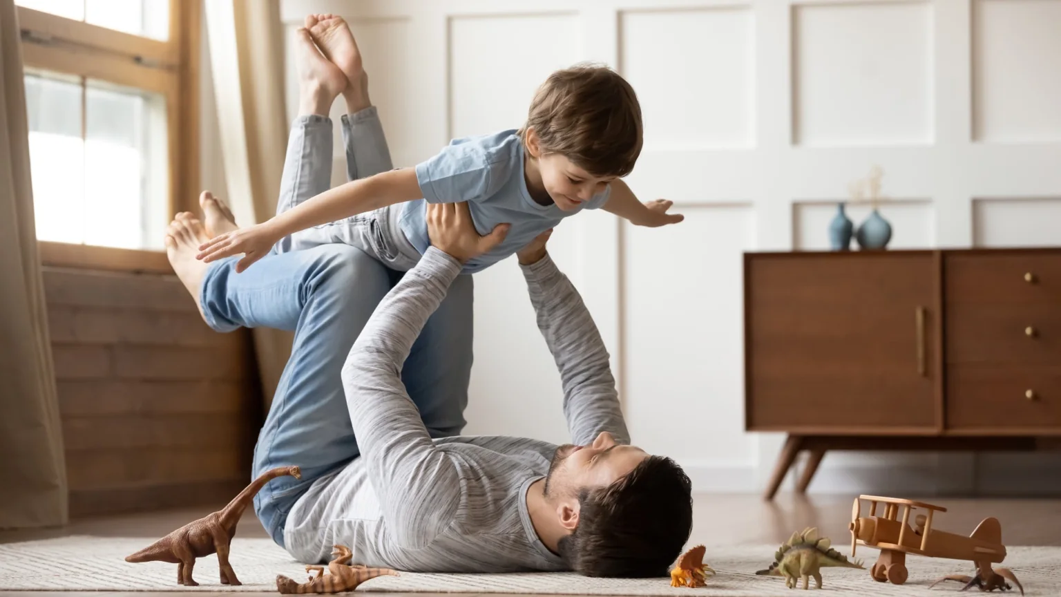 Father playing with his young son in a bright living room