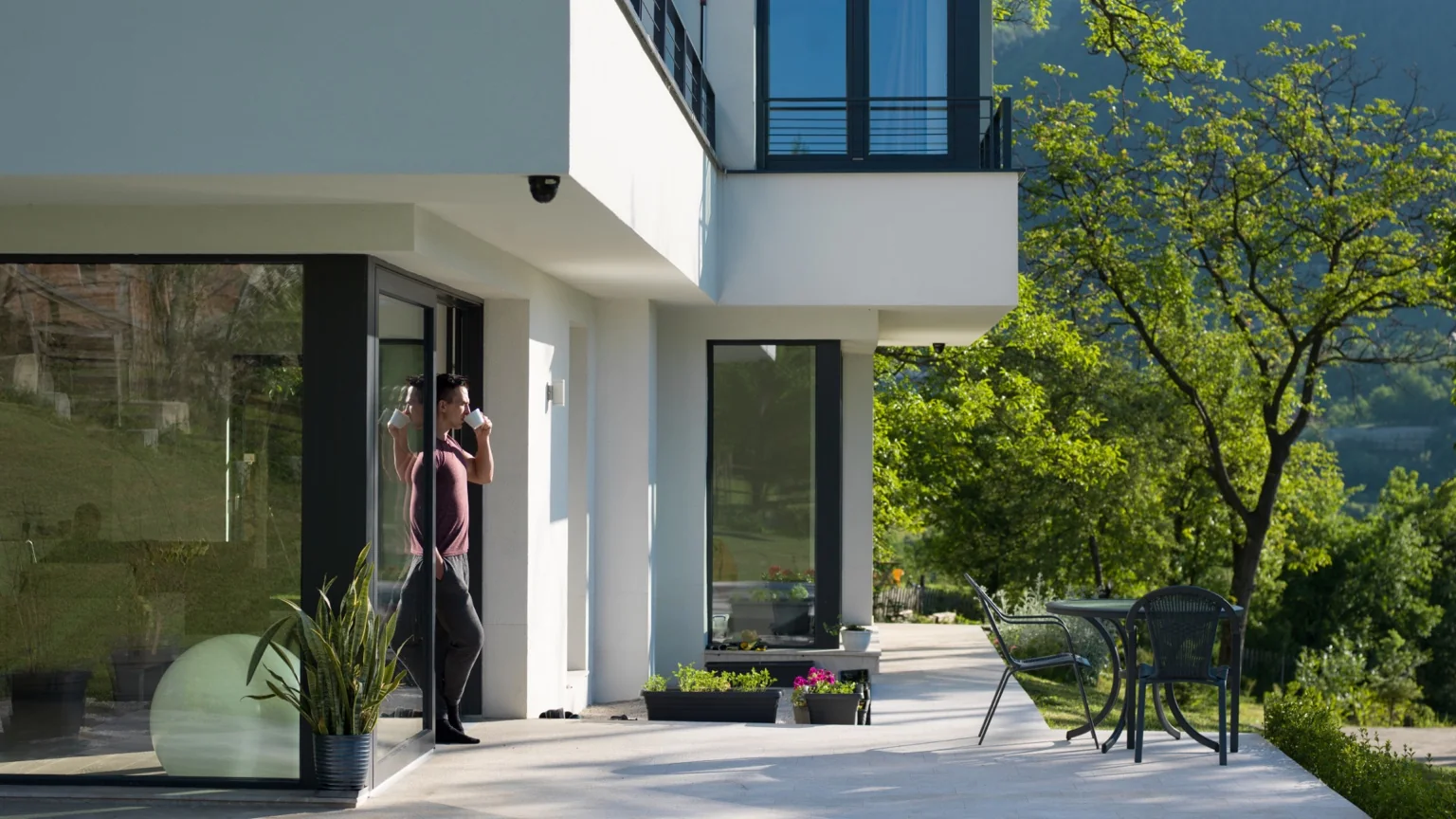 Woman standing inside a modern home with glass doors open to a patio
