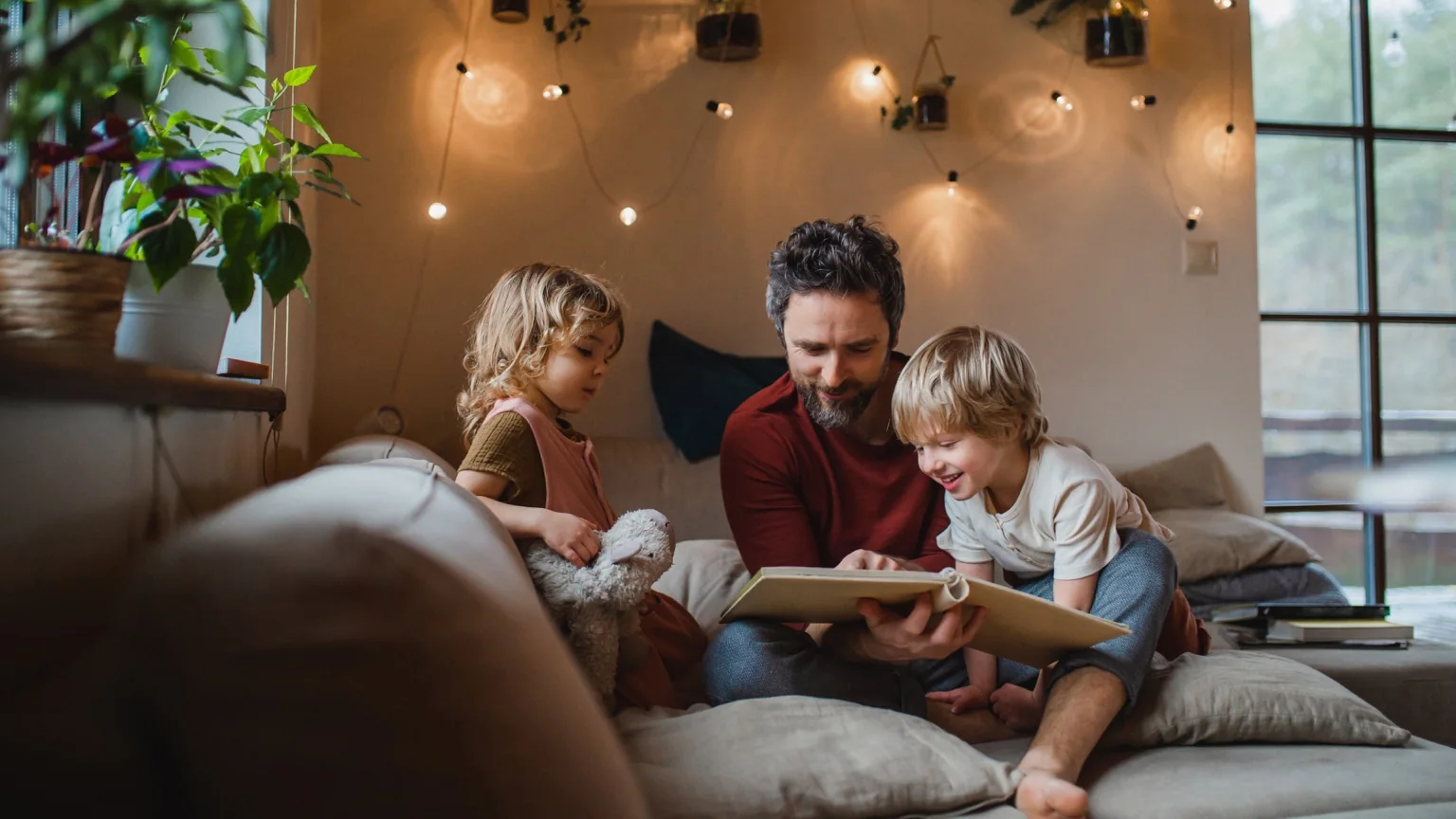 Father reading with his two children beneath warm string lights