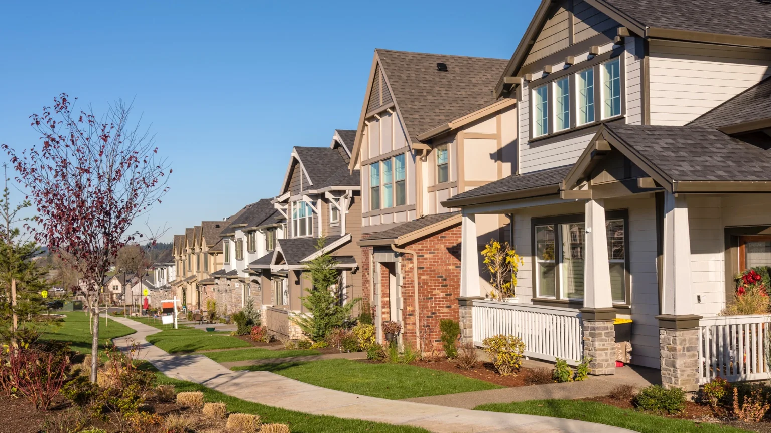 Tree-lined neighborhood of well-kept homes beneath a blue sky