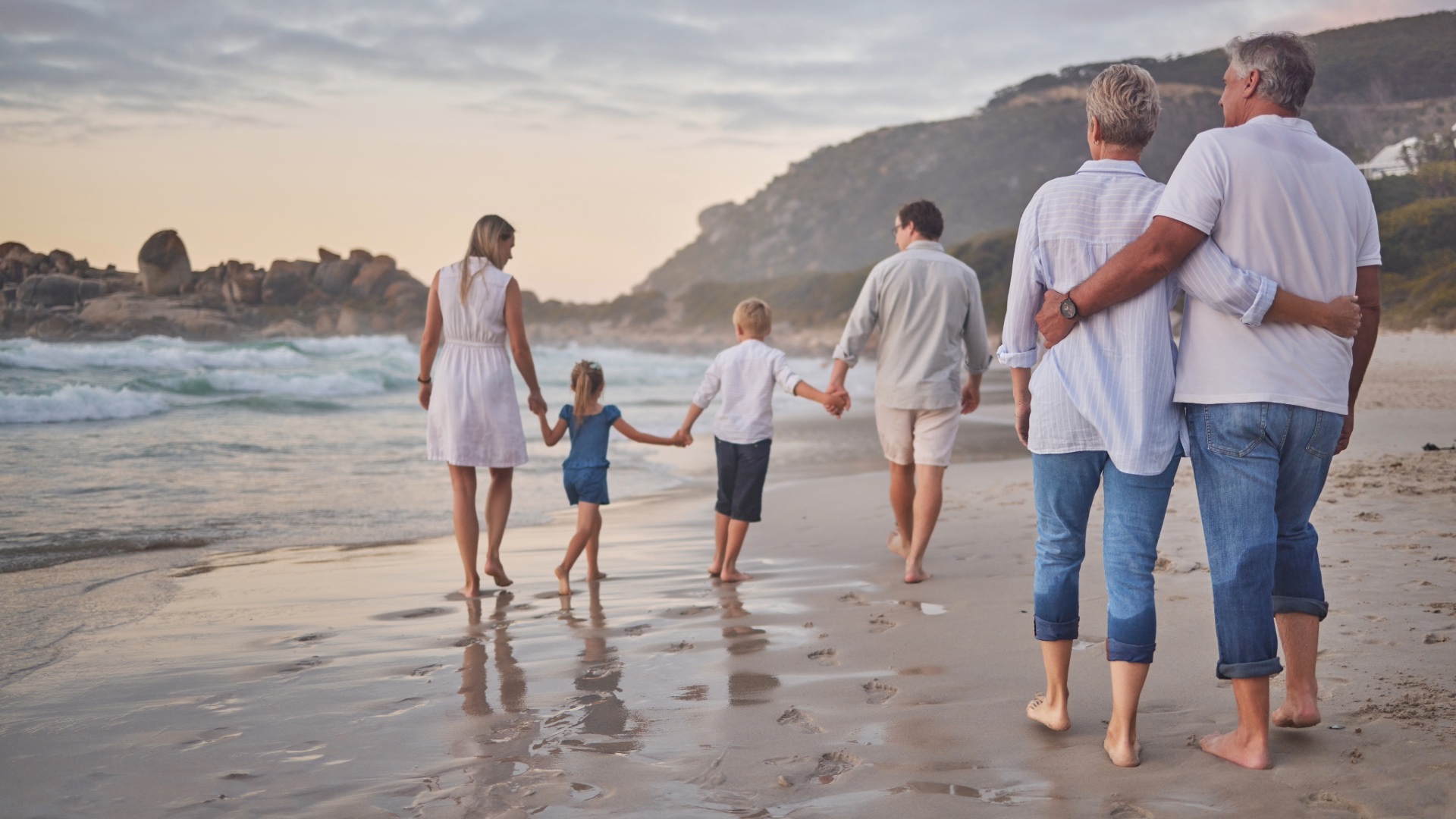 Multi-generational family walking together along a beach