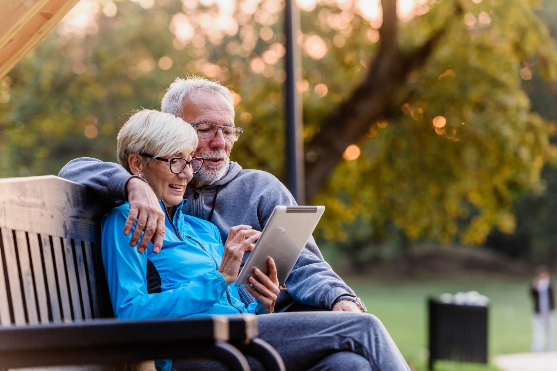 Older couple reviewing information together on a tablet in a park