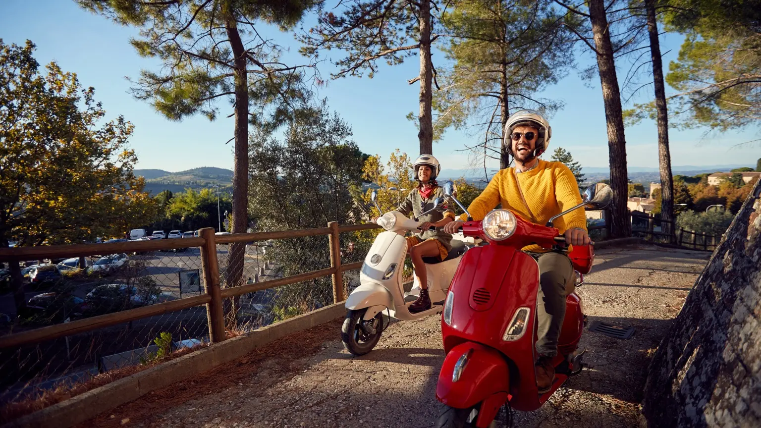 Two riders enjoying a scenic trip on red and white scooters