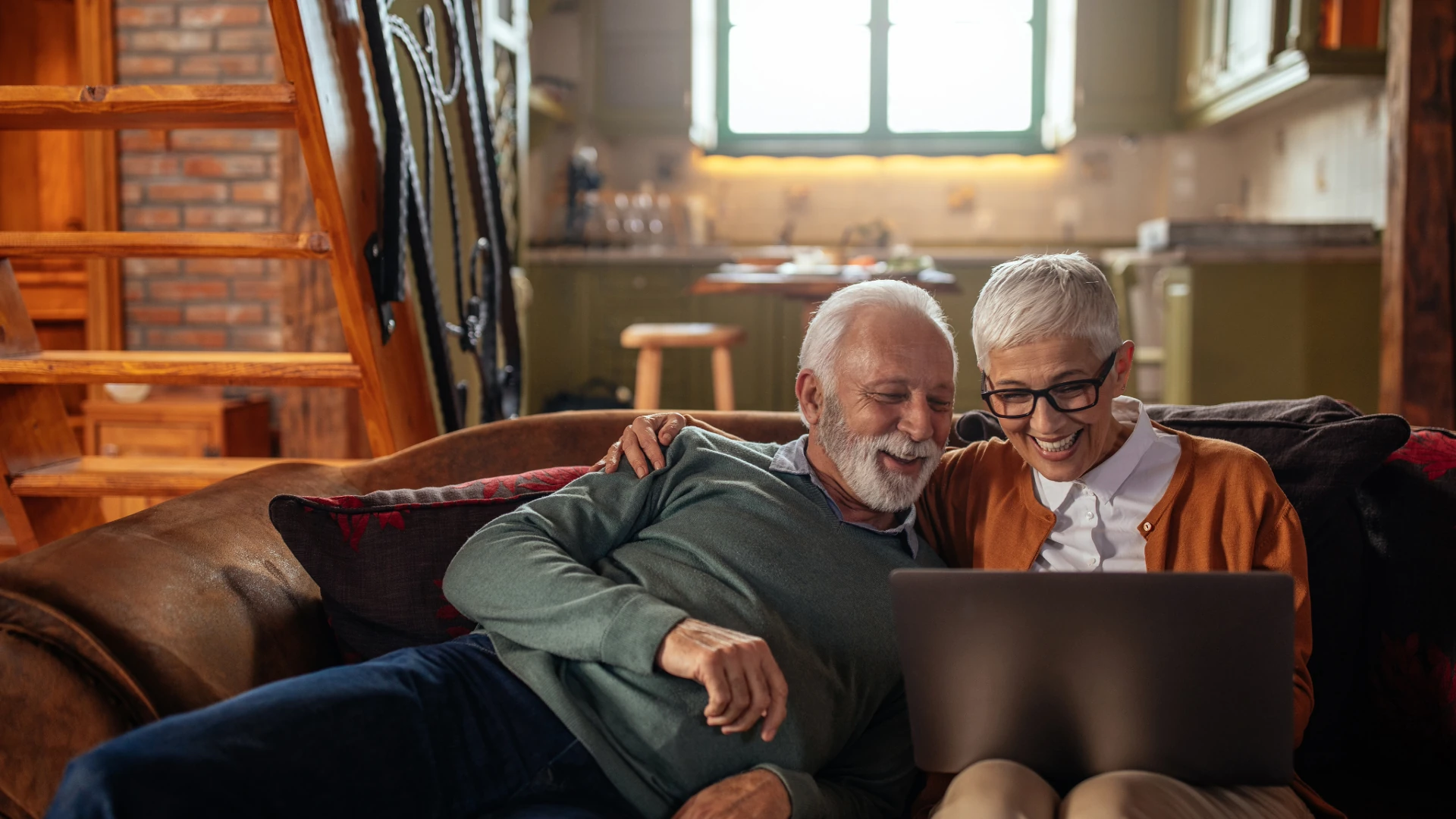 Retired couple reviewing a laptop together on their sofa
