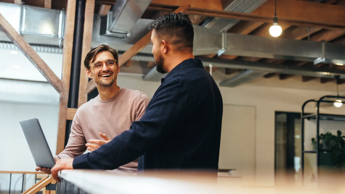 Two coworkers talking beside a laptop