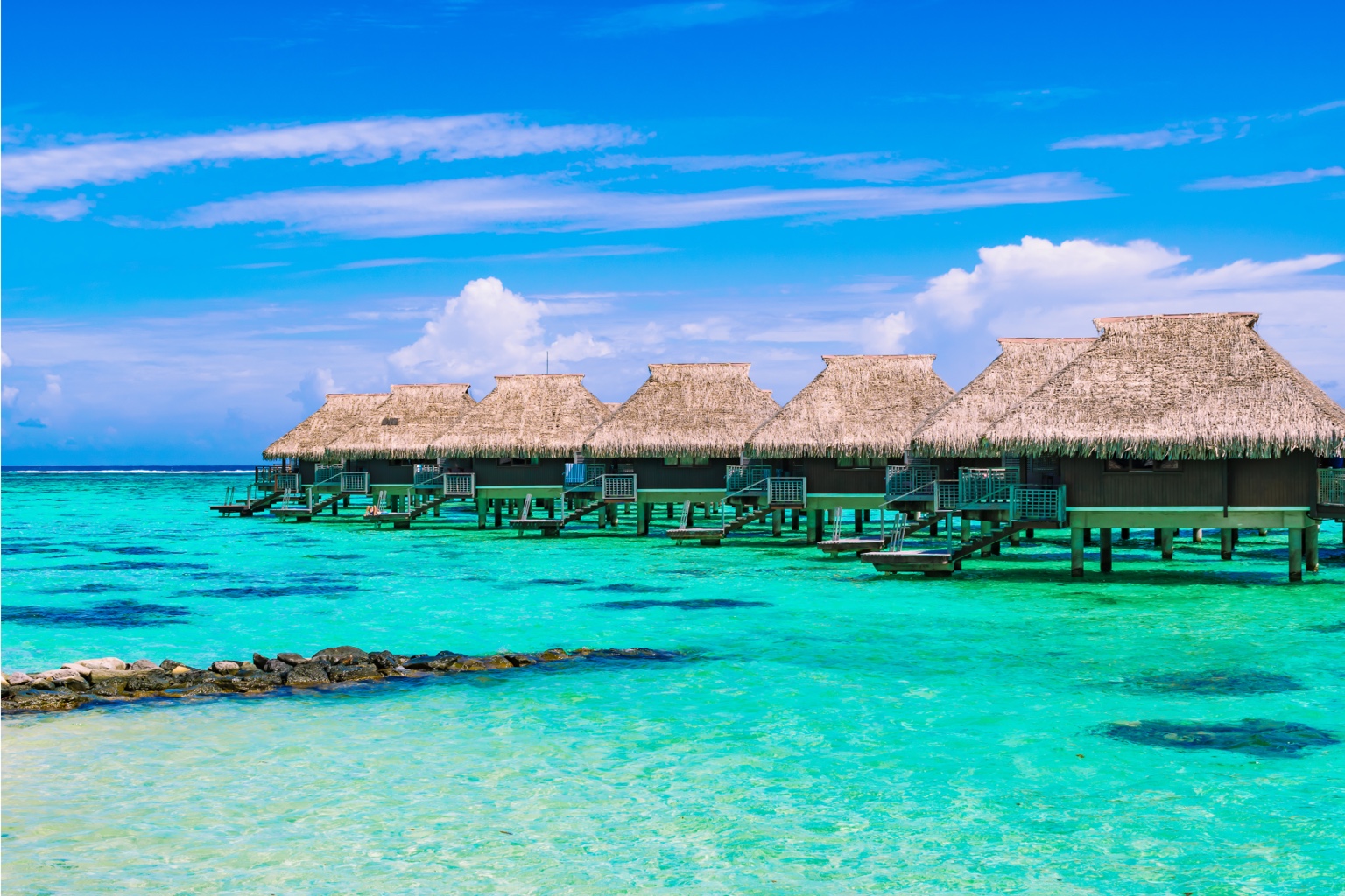 Overwater bungalows surrounded by turquoise tropical water