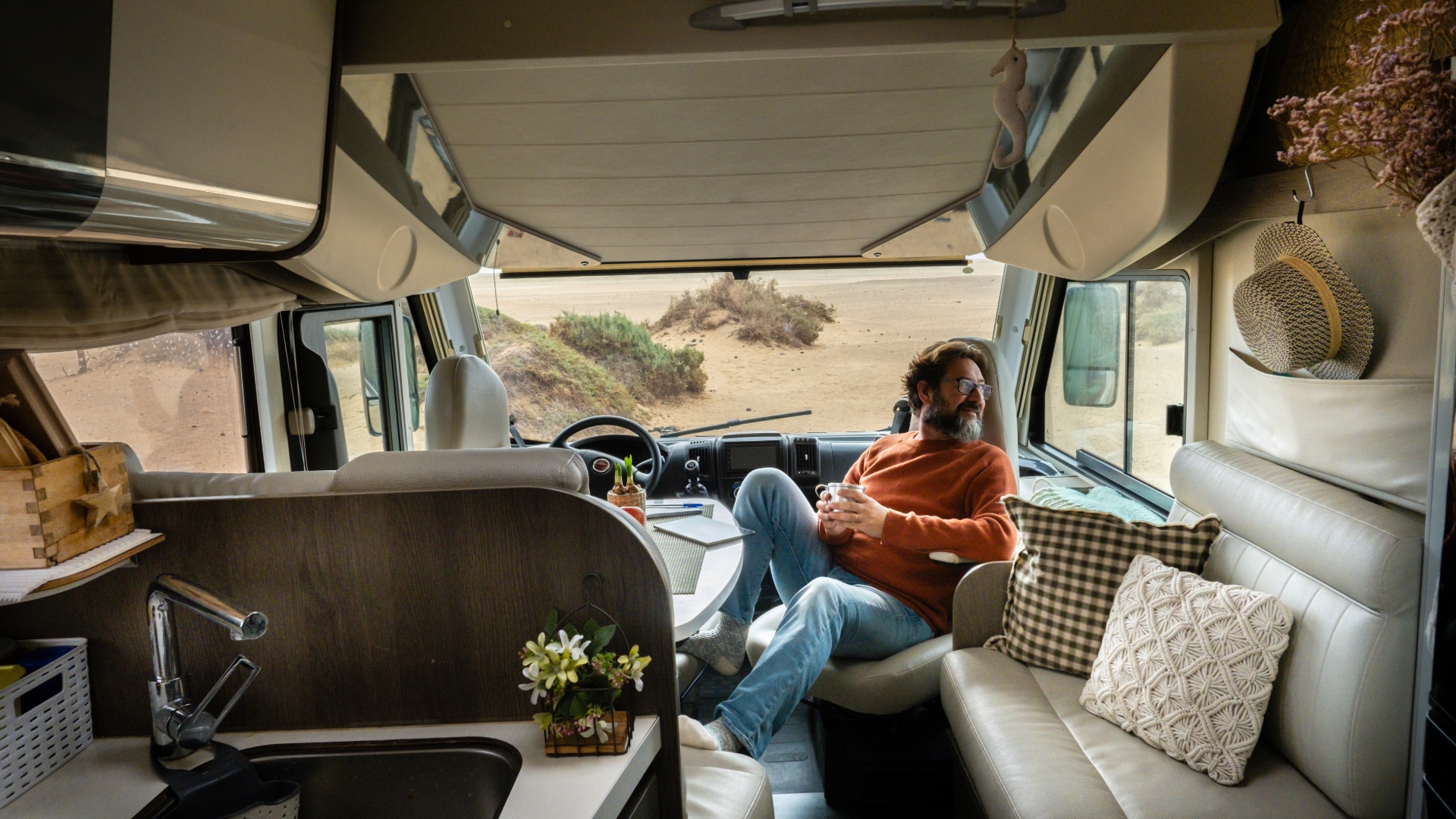 Traveler relaxing inside a motorhome by the beach