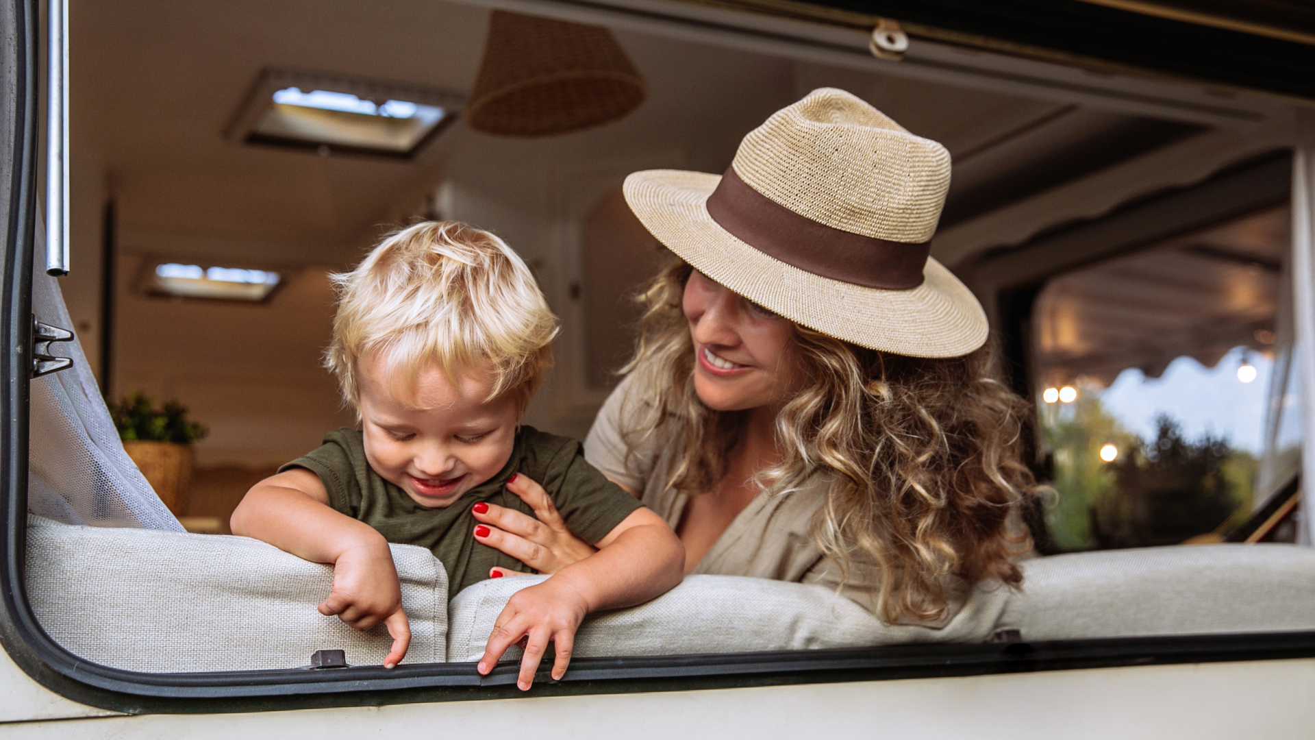 Mother and son smiling at a travel trailer window