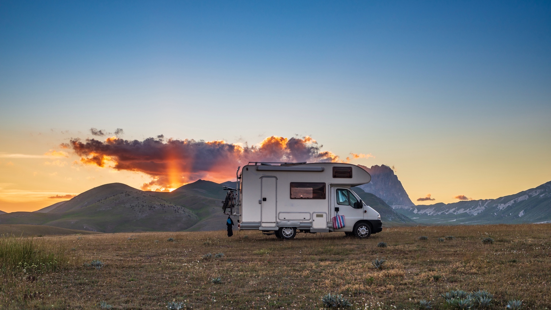 Motorhome parked in a mountain meadow at sunset